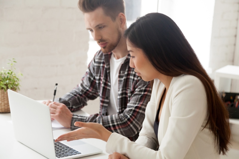 AC causing an electric bill to spike. Couple sitting together at at a computer.