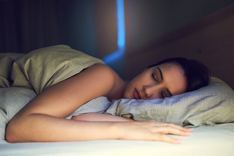 Photo of a young woman sleeping soundly in her bed.