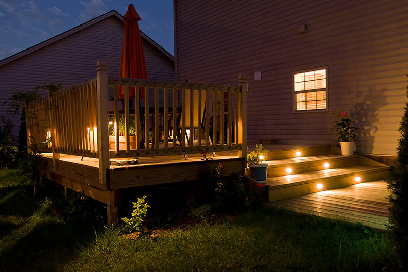 Wooden deck and patio of family home at night.