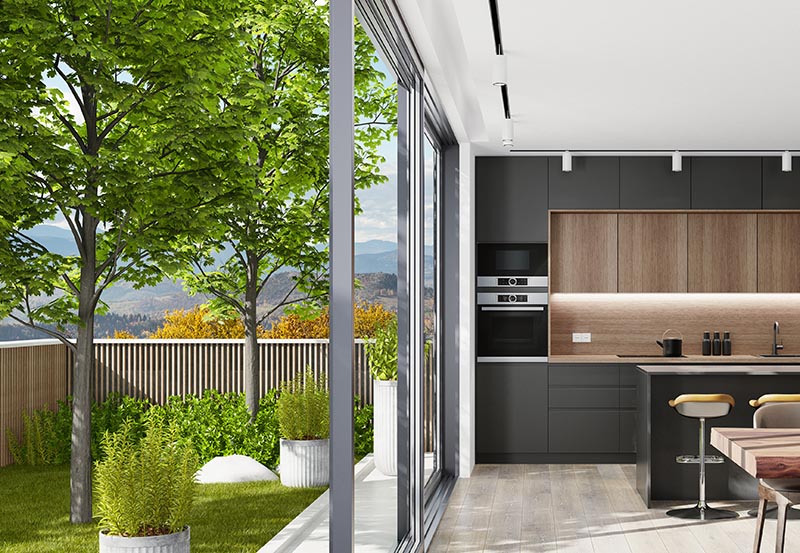 The backyard of a home can be seen on the left and the inside of the kitchen can be seen on the right.