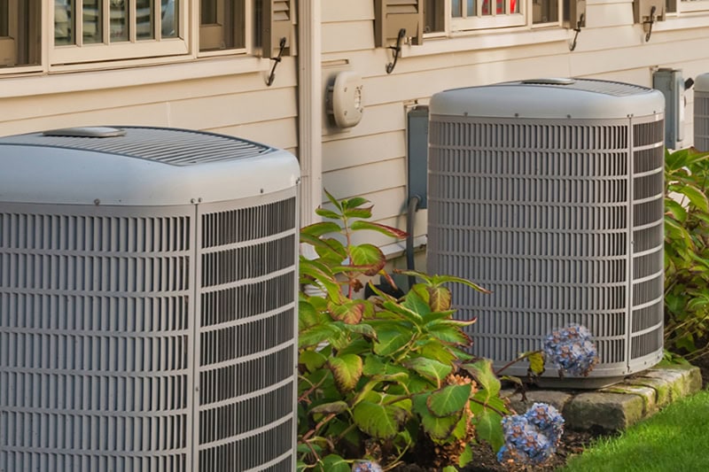Why Take the Risk? The Dangers of Buying an AC Online. Photo of two HVAC units installed outside of a home or building.