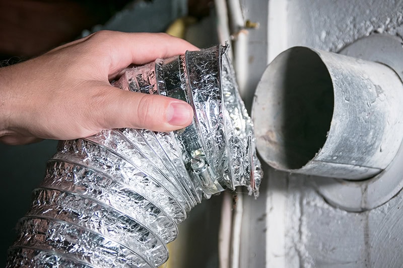 Duct Cleaning. Close up photo of a person pulling a dryer vent apart to clean.
