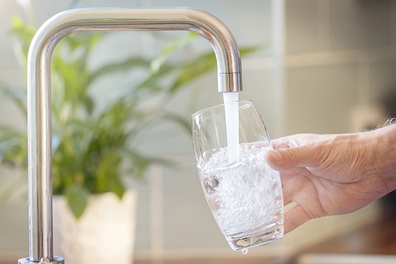 Filling up a glass with water from kitchen tap.